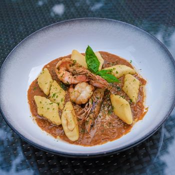 Serving of gnocchi pasta with red curry sauce and shrimp in Thailand.