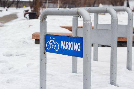 Empty bike parking in snowy public park at cold white winter, urban bicycle station in city recreation zone with cloudy weather