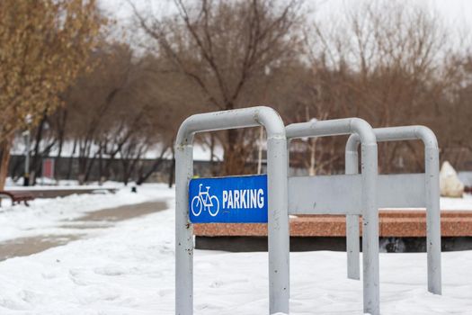 Empty bike parking in snowy public park at cold white winter, urban bicycle station in city recreation zone with cloudy weather