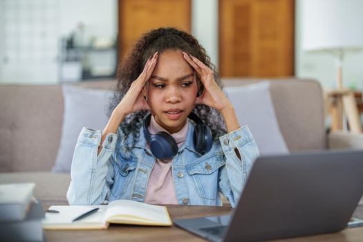 Portrait of an African American using computers and notebooks online and showing stressed faces and gestures in lessons learned