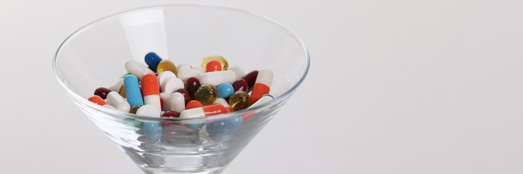 Glass with lot of multicolored medical capsules on white background closeup. Polypharmacy concept