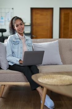 Portrait of an African American sitting on the sofa and working on a computer at home