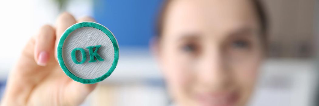 Woman holding green ink stamp OK in her hand closeup.