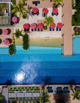 Aerial view from above at pool, tropical swimming pool from above with a drone. Men and women relaxing at a luxury pool during a honeymoon