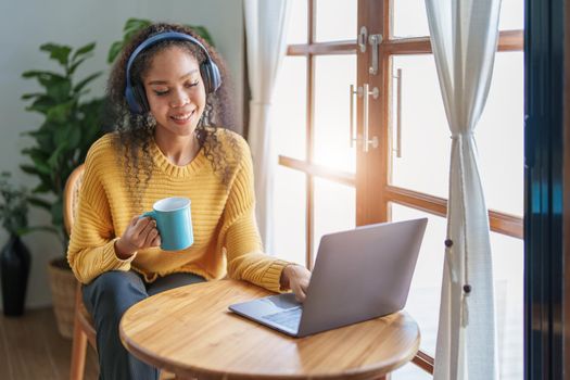 Portrait of an African American wearing headphones holding a coffee cup and using a computer.