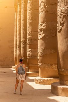 Vertical photo of a female tourist facing the columns of an egyptian temple in Karnak, Egypt