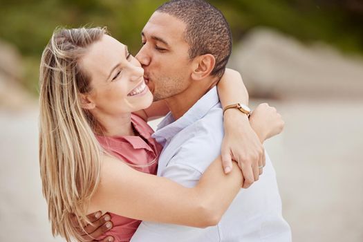 Smile, love and happy couple kiss on the cheek on honeymoon vacation outdoors to celebrate their marriage. Happiness, interracial and smiling woman enjoys traveling on romantic trip with her partner.
