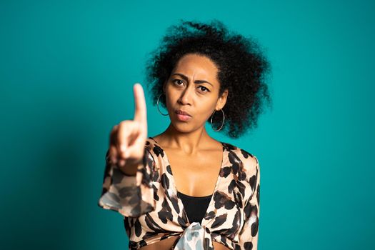 Mixed race woman disapproving with NO hand sign gesture. Denying, rejecting, disagree, portrait of beautiful girl on blue background. High quality photo