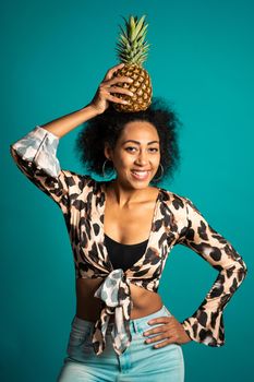 Playful young african american woman with fresh pineapple on head as crown. Healthy exotic lifestyle and eating concept. High quality photo