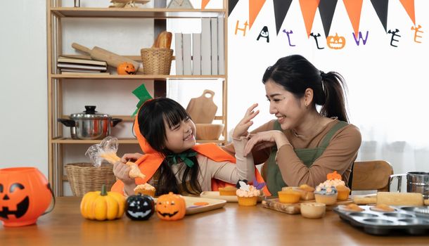 Happy Halloween family mother and daughter getting ready for holiday and baking cookies.