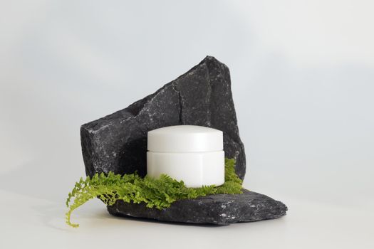 Unbranded natural cosmetic cream packaging standing on stone podium. Cream presentation on the white background. Mockup. Trending concept in natural materials. Natural cosmetic, skincare