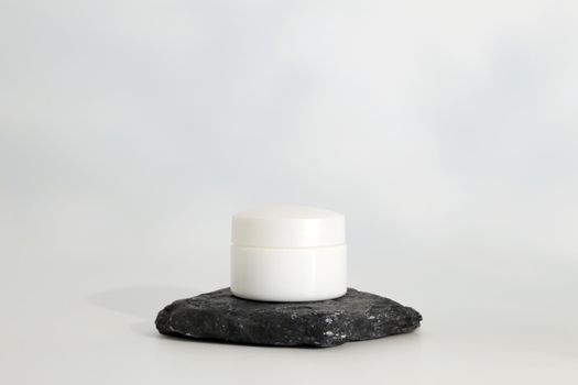 Unbranded natural cosmetic cream packaging standing on stone podium. Cream presentation on the white background. Mockup. Trending concept in natural materials. Natural cosmetic, skincare