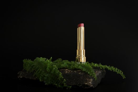 Lipstick standing on stone podium. Lipstick presentation on the black background