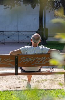 Man sits on a bench in the park to relax on a sunny day.