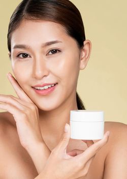 Closeup ardent woman smiling holding mockup product for advertising text place, light grey background. Concept of healthcare for skin, beauty care product for advertising.