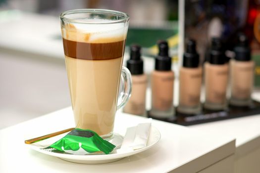 A cup of latte with candy on a saucer on the table in the manicure room. Manicure master place