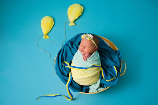 Ukrainian newborn in the studio patriotic blue yellow colors during the war in Ukraine 2022. A little baby, girl sleeps on isolated background