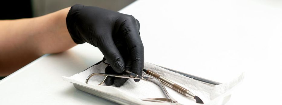 Professional manicure master prepares nail care tools on a white background with copy space