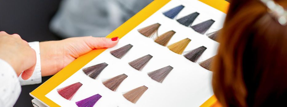 Young caucasian woman choosing a color from the hair color chart in a beauty salon