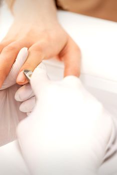 Manicure master uses manicure clippers removing cuticles on female nails in a beauty salon close up