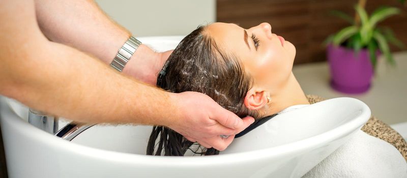 Beautiful caucasian woman washing hair in a beauty salon