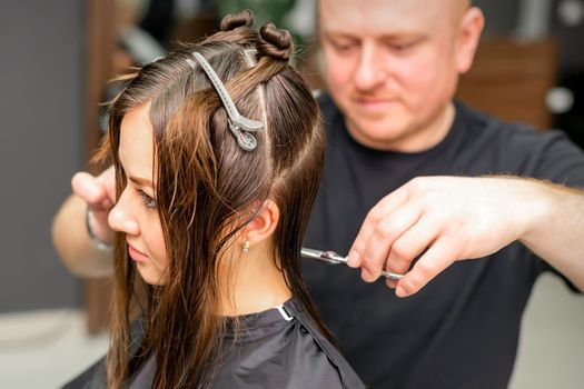 Male stylist cutting the hair of female client in professional beauty salon