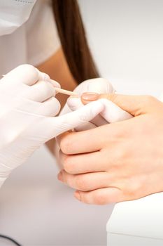 Young woman receiving pink or beige nail polish in a beauty salon