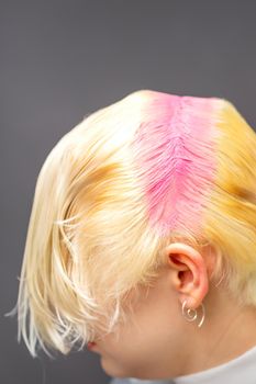 Young caucasian woman tints hair roots in pink color in a beauty salon