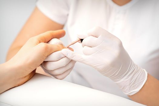 Young woman receiving pink or beige nail polish in a beauty salon