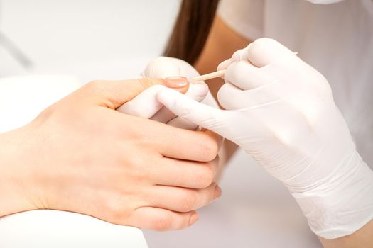 Young woman receiving pink or beige nail polish in a beauty salon