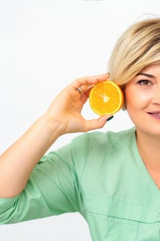 Portrait of young smiling blonde woman cosmetologist with halves of oranges on white background