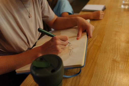 The girl draws in a sketchbook. Family confectionery studio. The girl came to the cafe to drink coffee and draw. Sketching in cafe.