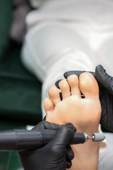 Peeling pedicure procedure on the sole from callus of the female foot by a pedicurist at a beauty salon