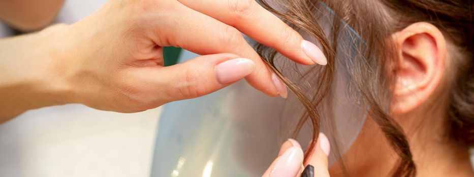 Close Up hairdresser stylist makes hairstyle for a young woman in a beauty salon