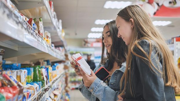 Two friends are in the shop buying biscuits and sweets