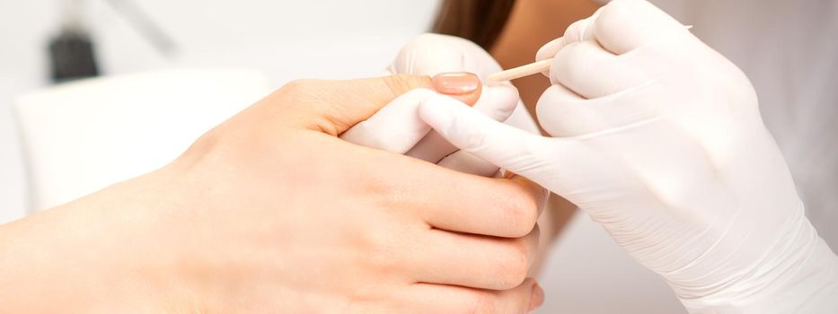 Young woman receiving pink or beige nail polish in a beauty salon