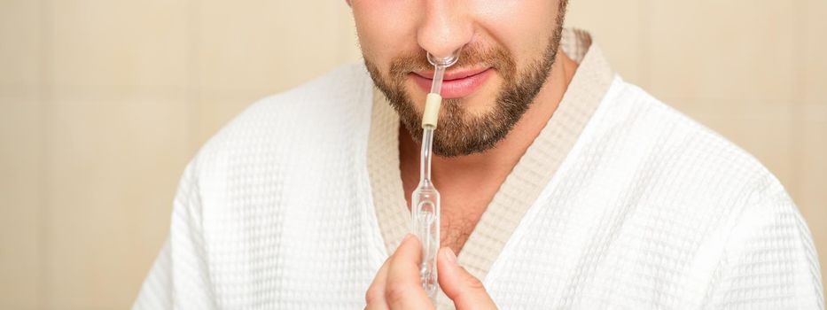 Young caucasian man receiving nasal inhalation Maholda with essential oil in the nose at a hospital