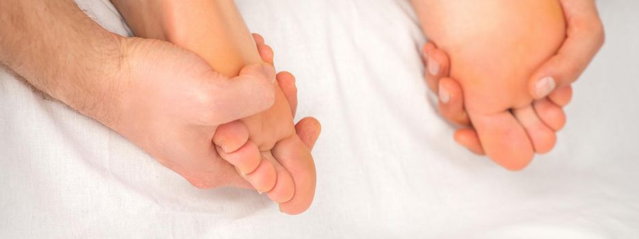 Relaxing double massage on the female feet by two masseurs in spa salon