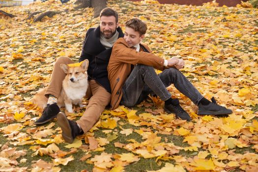 Father and son with a pet on a walk in the autumn park.