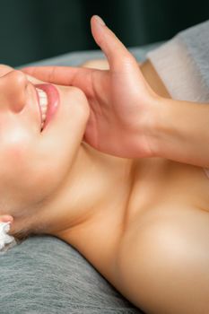 Doctor examining the beautiful face of young smiling woman in beauty clinic