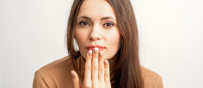 Young caucasian woman posing with fashion beige nails and sensual lips in studio