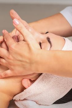 Beautiful caucasian young woman getting a facial massage at a beauty salon