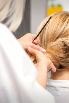 Close-up hairdresser styling blonde hair on the back of the head in a beauty salon