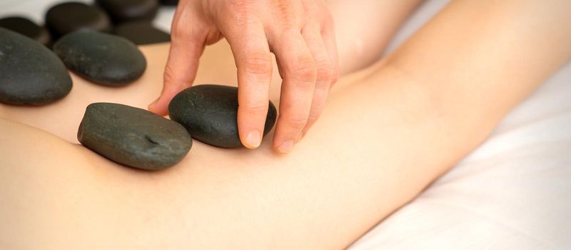 A woman getting spa hot stone therapy legs massage procedure in a beauty salon