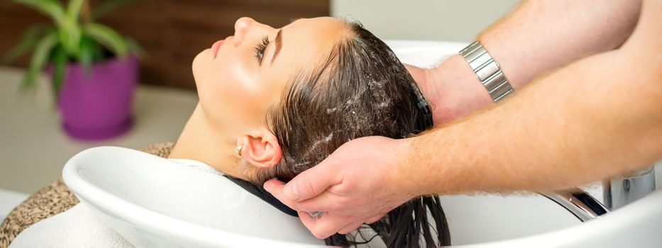 Beautiful caucasian woman washing hair in a beauty salon