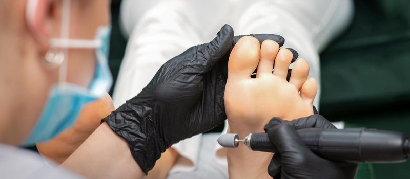 Peeling pedicure procedure on the sole from callus of the female foot by a pedicurist at a beauty salon