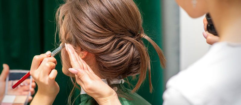 Stylist and makeup artist preparing bride before the wedding in a beauty salon