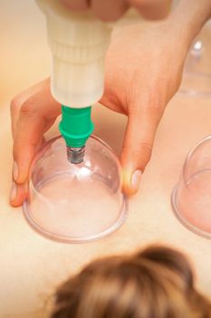 Woman receiving vacuum cupping treatment on back laying on the chest in massage salon
