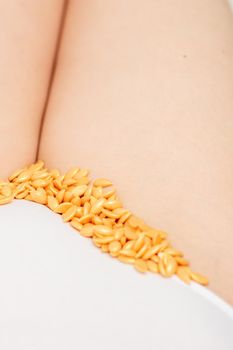 Sugaring concept. Wax granules lying in a row on female bikini area close up
