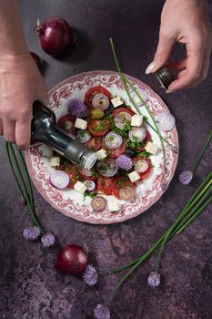 cherry tomato salad with purple onion rings dressed with balsamic dressing and olive oil with feta cheese and olives on a dark purple background, step by step recipe,flat lay